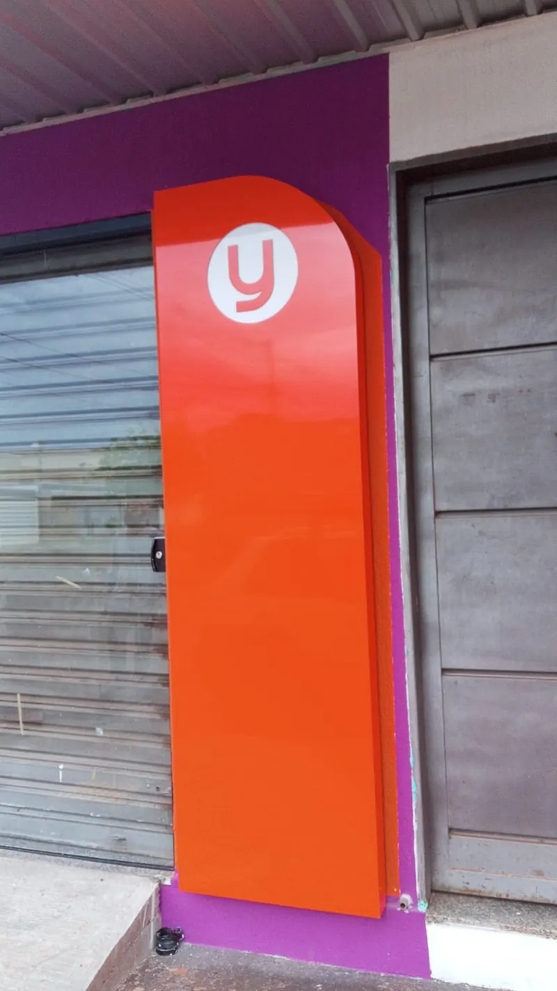 Painel em ACM laranja com logo da Lavey Lavanderia Express na entrada da loja